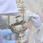 Un acólito recarga un incensario durante un procesión 