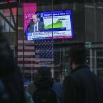 Peatones caminan junto a la Bolsa de Nueva York el día que empezó a cotizar la red social de Donald Trump