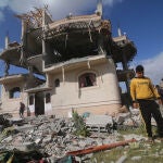Palestinos frente a un edificio destruido por un bombardeo del Ejército de Israel contra la ciudad de Rafá, en el sur de la Franja de Gaza