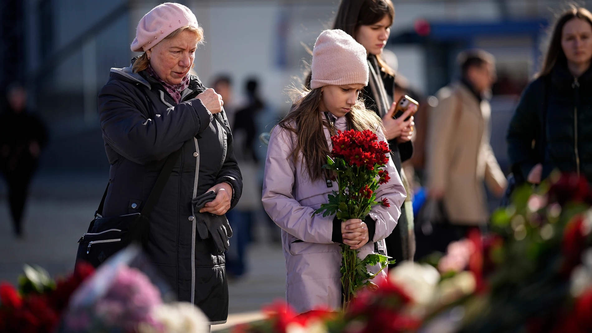 People stand at a makeshift memorial in front of the Crocus City Hall on the western outskirts of Moscow, Russia, Wednesday, March 27, 2024. Russian officials persisted Tuesday in saying Ukraine and the West had a role in last week's deadly Moscow concert hall attack despite vehement denials of involvement by Kyiv and a claim of responsibility by an affiliate of the Islamic State group. (AP Photo/Alexander Zemlianichenko)