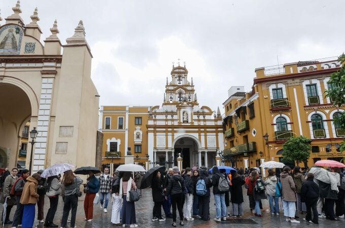 Feligreses hacen cola con paraguas en la Basílica de la Macarena de Sevilla