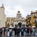 Feligreses hacen cola con paraguas en la Basílica de la Macarena de Sevilla