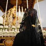 Una mujer vestida de mantilla reza a La Virgen del Mayor Dolor y Traspaso, a 28 de marzo de 2024, en Sevilla