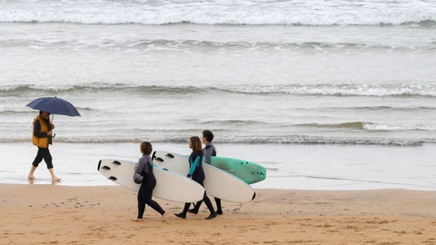 Gente paseando bajo la lluvia en la Playa de San Lorenzo de Gijón