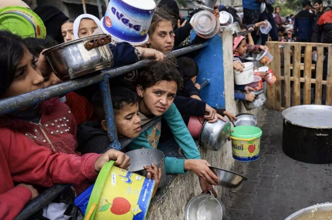 Un grupo de niños palestinos espera el reparto de comida en un campo de refugiados en Rafah