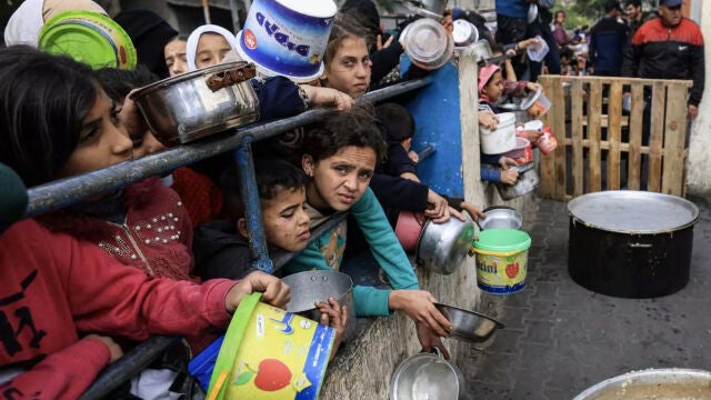Un grupo de niños palestinos espera el reparto de comida en un campo de refugiados en Rafah