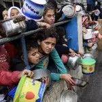 Un grupo de niños palestinos espera el reparto de comida en un campo de refugiados en Rafah