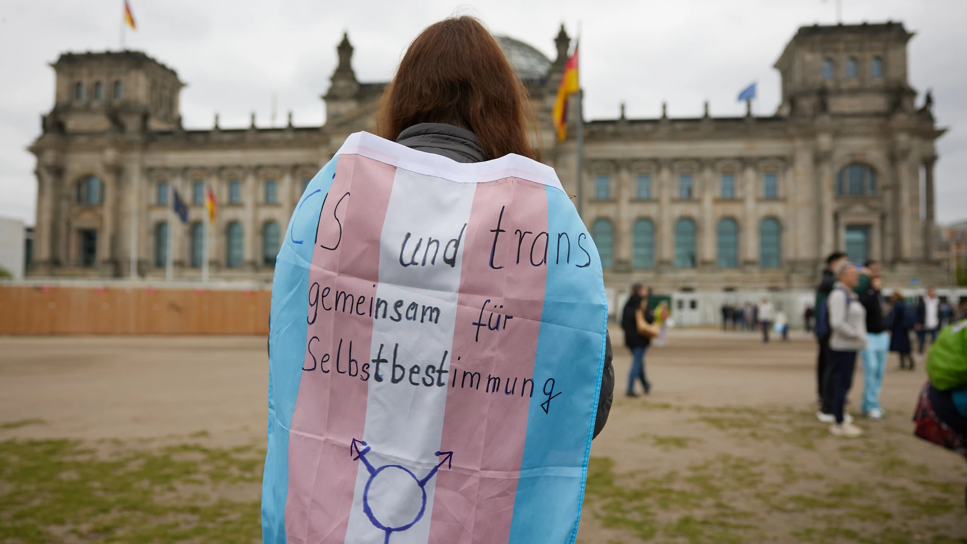 12 April 2024, Berlin: A person stands in front of the Bundestag with a transgender pride flag during a protest against the Self-Determination Act by women's groups. Photo: Joerg Carstensen/dpa 12/04/2024 ONLY FOR USE IN SPAIN