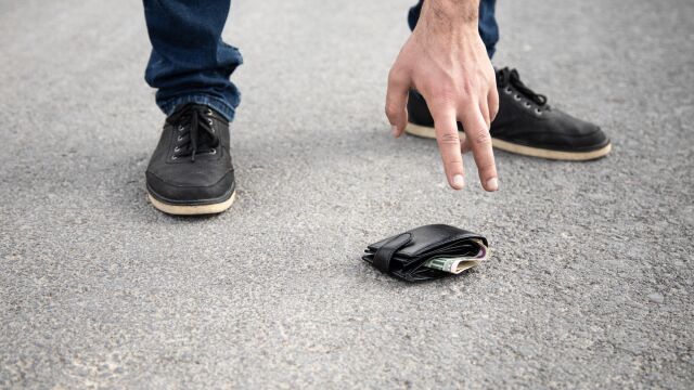 Persona recogiendo una cartera del suelo