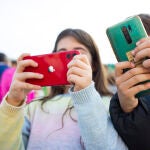 Una niña y un niño con sus móviles