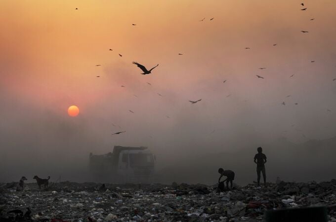 FILE- In this Oct. 17, 2014, file photo, a thick blanket of smoke is seen against the setting sun as young ragpickers search for reusable material at a garbage dump in New Delhi, India. India launched the Air Quality Index Friday to measure air quality across the nation that is home to some of the most polluted cities in the world. A groundbreaking agreement struck Wednesday, Nov. 12, 2014, by the United States and China puts the world's two worst polluters on a faster track to curbing the heat-trapping gases blamed for global warming. (AP Photo/Altaf Qadri, File)