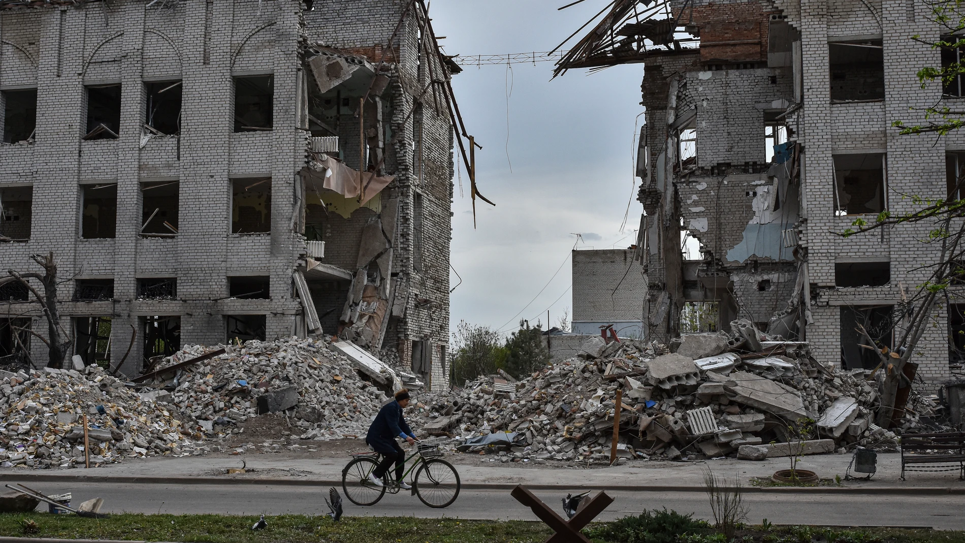 A local woman rides a bicycle in front of a building which was destroyed by a Russian airstrike in the frontline town of Orikhiv, Ukraine, on Thursday, April 18, 2024. (AP Photo/Andriy Andriyenko)