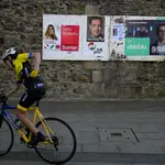 A cyclist passes electoral posters with candidates Pello Otxandiano for EH Bildu, a coalition of pro-independence and nationalist Basque parties, right, Imanol Pradales fo PNV (Basque nationalist party) and Alba Garcia for Sumar, left, in Otxandio, northern Spain.
