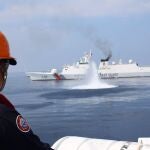 A Filipino coastguard personnel on a patrol vessel viewing a Chinese Coast Guard (CCG) ship firing a water cannon at the vicinity of Scarborough Shoal in the disputed South China Sea