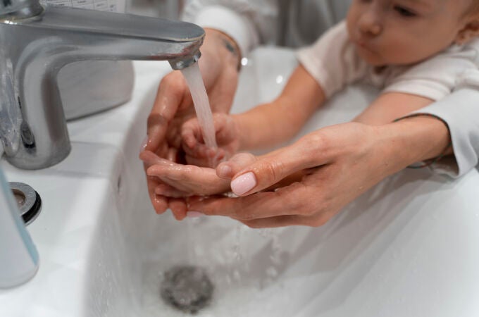 Un pequeño se lava las manos con la ayuda de su madre