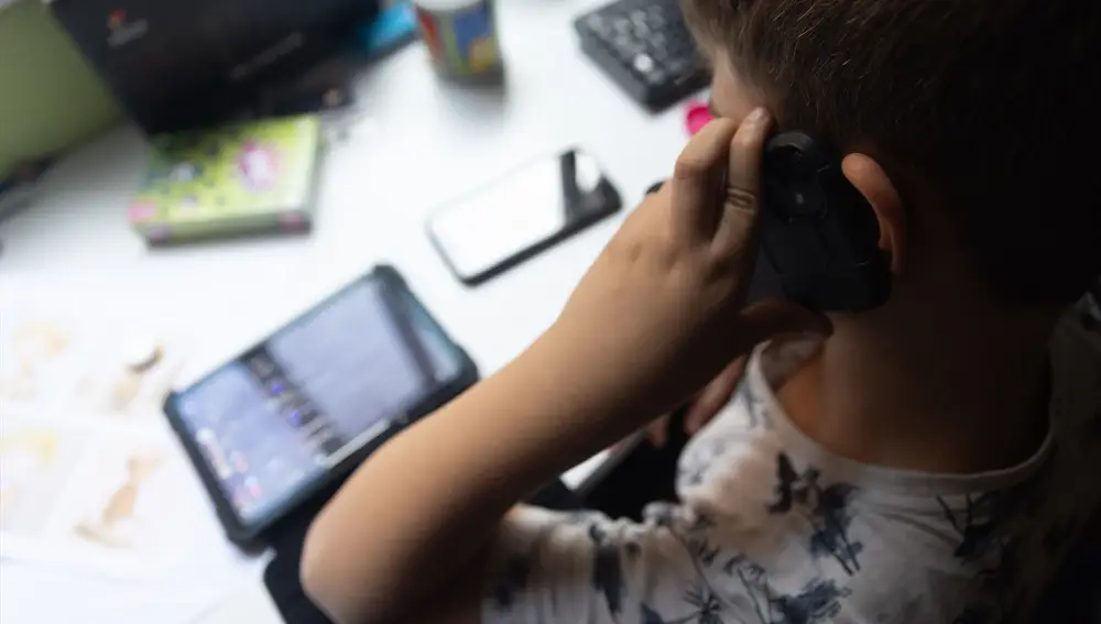 Un niño usa el teléfono móvil y una tablet, a 18 de octubre de 2023, en Madrid (España)