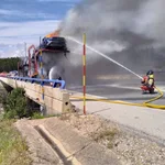 Un bombero trata de apagar las llamas del vehículo siniestrado