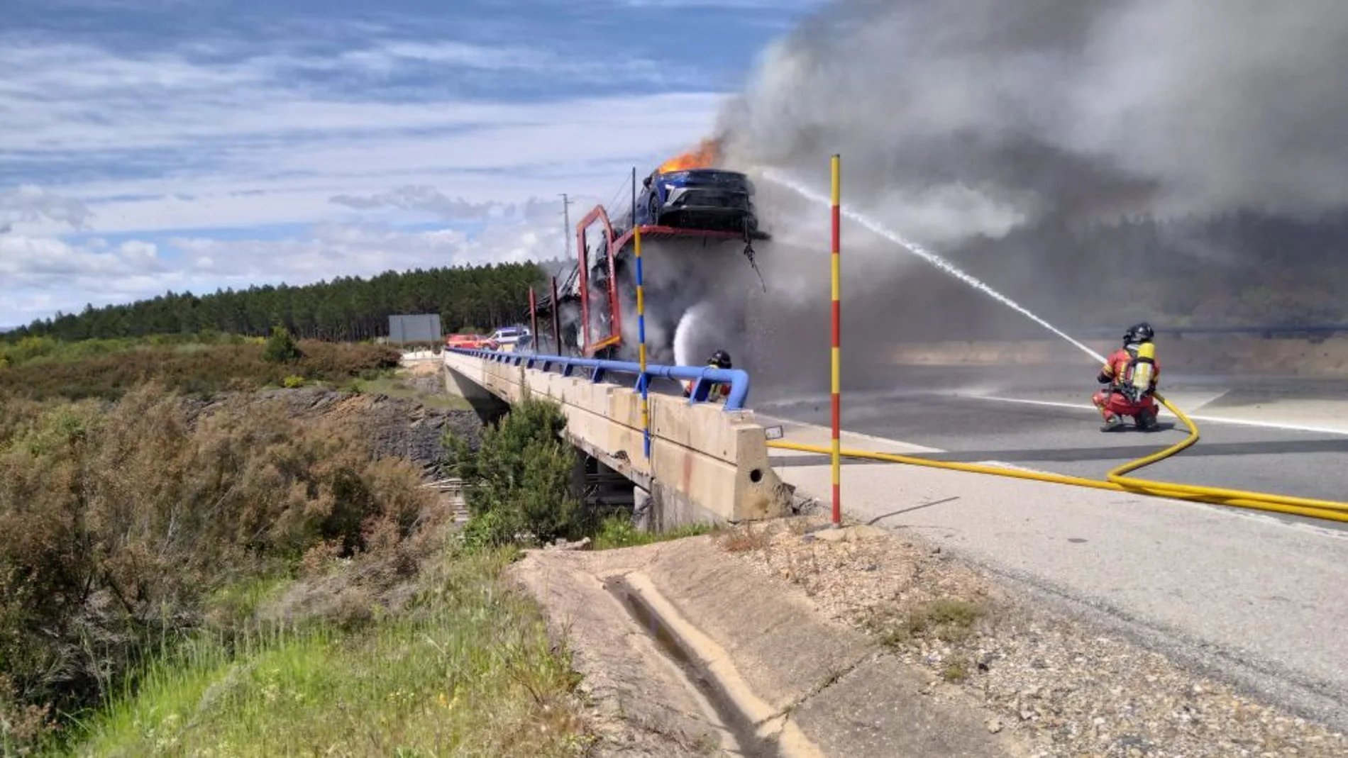 Un bombero trata de apagar las llamas del vehículo siniestrado