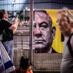 Una mujer fotografía un cartel con la imagen de Benjamin Netanyahu en una calle de Tel Aviv