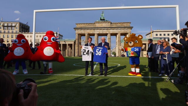 El presidente francés, Emmanuel Macron, y su homólogo alemán, Frank Walter Steinmeier, intercambian camisetas de sus selecciones de fútbol frente a la puerta de Brandenburgo