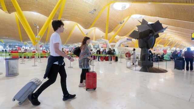 Un grupo de personas caminan por uno de los pasillos de las instalaciones de la terminal T4 del aeropuerto de Adolfo Suárez-Madrid Barajas.