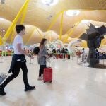 Un grupo de personas caminan por uno de los pasillos de las instalaciones de la terminal T4 del aeropuerto de Adolfo Suárez-Madrid Barajas.