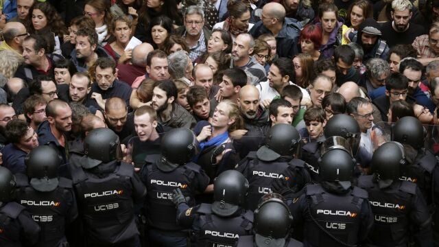 Agentes antidisturbios de la Policía Nacional forman un cordón de seguridad en los alrededores del colegio Ramón Llull de Barcelona. Policía Nacional y Guardia Civil han desplegado a sus agentes en varios colegios electorales de Barcelona para impedir el referéndum del 1-O, suspendido por el Tribunal Constitucional (TC), lo que ha originado momentos de tensión y algún forcejeo con las personas concentradas ante los locales. 