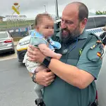 Agente de la Guardia Civil de Lepe (Huelva) con el bebé rescatado en brazos. GUARDIA CIVIL