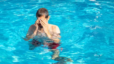 Un hombre se frota los ojos en una piscina