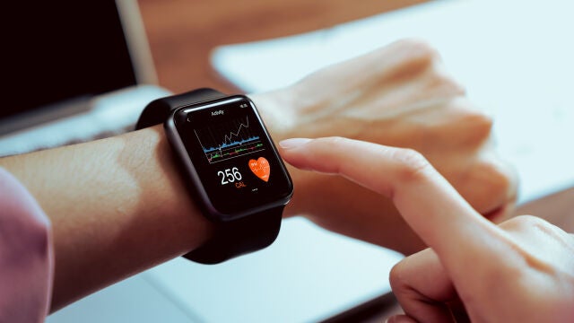 Primer plano de la mano tocando el reloj inteligente con la aplicación de salud en la pantalla. 