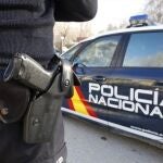 Un agente y un coche de la Policía Nacional.