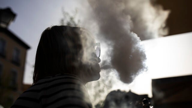Una chica fuma tabaco en un vapeador en una terraza de Madrid. 