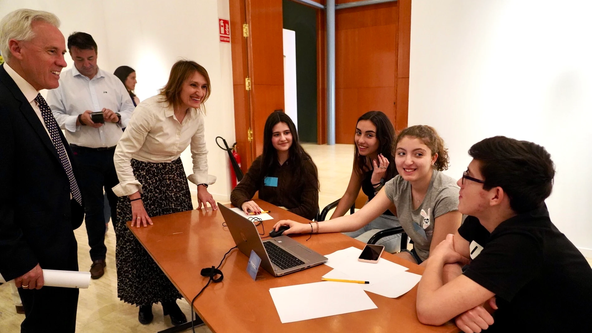La consejera de Educación, Rocío Lucas, dialoga con un grupo de estudiantes que trabajan con un dispositivo digital