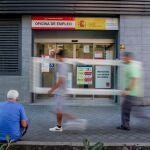 Varias personas pasan por delante de la oficina del SEPE del Paseo de las Acacias, en Madrid (España). 