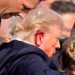 Republican candidate Donald Trump is seen with what appears to be blood on his face surrounded by secret service agents as he is taken off the stage at a campaign event at Butler Farm Show Inc. in Butler, Pennsylvania, July 13, 2024. - Republican candidate Donald Trump was evacuated from the stage at today's rally after what sounded like shots rang out at the event in Pennsylvania, according to AFP. The former US president was seen with blood on his right ear as he was surrounded by security 