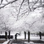 Un hombre con un paraguas camina en un parque durante la nevada en Romainvile, cerca de París