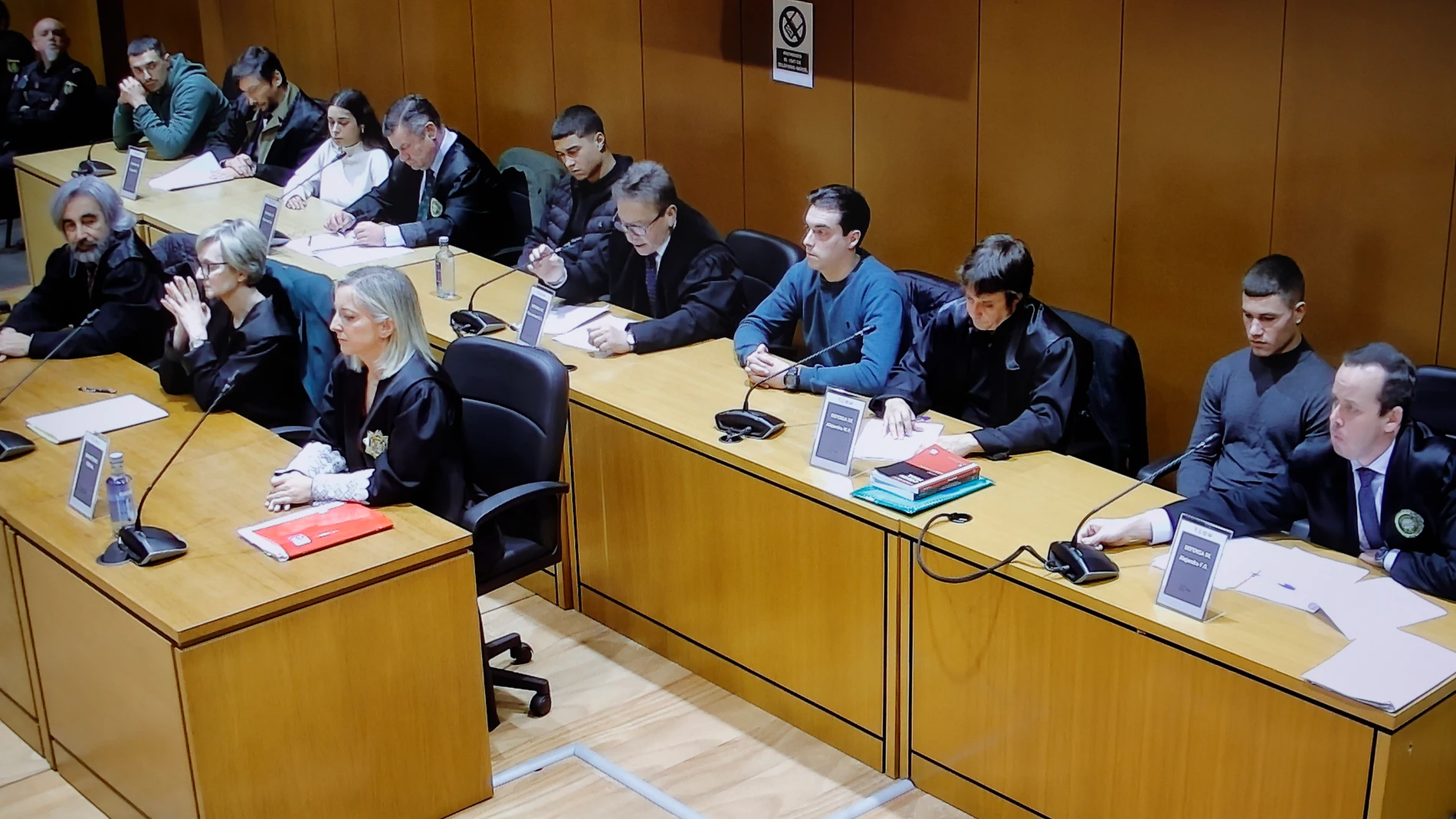 A CORUÑA, 24/11/2024.- Foto tomada a la pantalla de circuito cerrado de la Audiencia Provincial de A Coruña de los cinco acusados por el asesinato del joven brasileño Samuel Luiz, Catherine Silva (i), Alejandro Freire "Yumba" (2i), Diego Montaña (c), Kaio Amaral (2d) y Alejandro Míguez (d), acompañados por sus abogados, durante la lectura del veredicto celebrada este domingo en la Audiencia Provincial de A Coruña. EFE/Cabalar