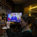 Una camarera sirve una cerveza en un bar de Versalles durante el discurso a la nación del presidente francés, Emmanuel Macron