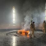 Rebel fighters stand next to the burning gravesite of Syria's late president Hafez al-Assad at his mausoleum in the family's ancestral village of Qardaha in the western Latakia province on December 11, 2024, after it was stormed by opposition factions. - The father and predecessor of Syria's ousted president Bashar al-Assad died in 2000. 