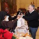 El presidente de las Cortes, Carlos Pollán, compra productos de repostería de convento en uno de los expositores presentes en la feria
