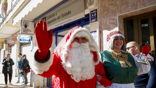 Una persona disfrazada de Papá Noel saluda ante la administración número 5 de Catarroja, en la zona cero de la dana del 29 de octubre, que ha vendido una serie del quinto premio, el 11.840