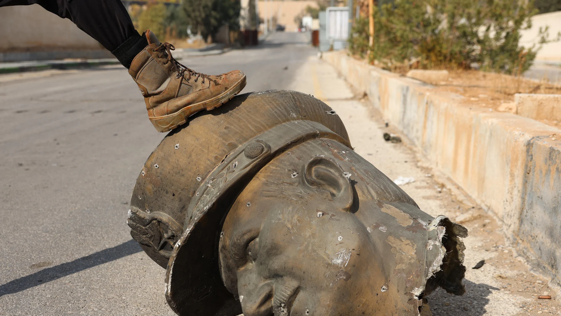 An opposition fighter steps on the decapitated statue of late Syrian President Hafez al-Assad in Mezzeh Military Airport in Damascus, Syria 12 December 2024. The Israeli army stated it has conducted airstrikes across Syria targeting strategic weapons stockpiles. Rebels ousted Syrian president Bashar al-Assad 08 December 2024.