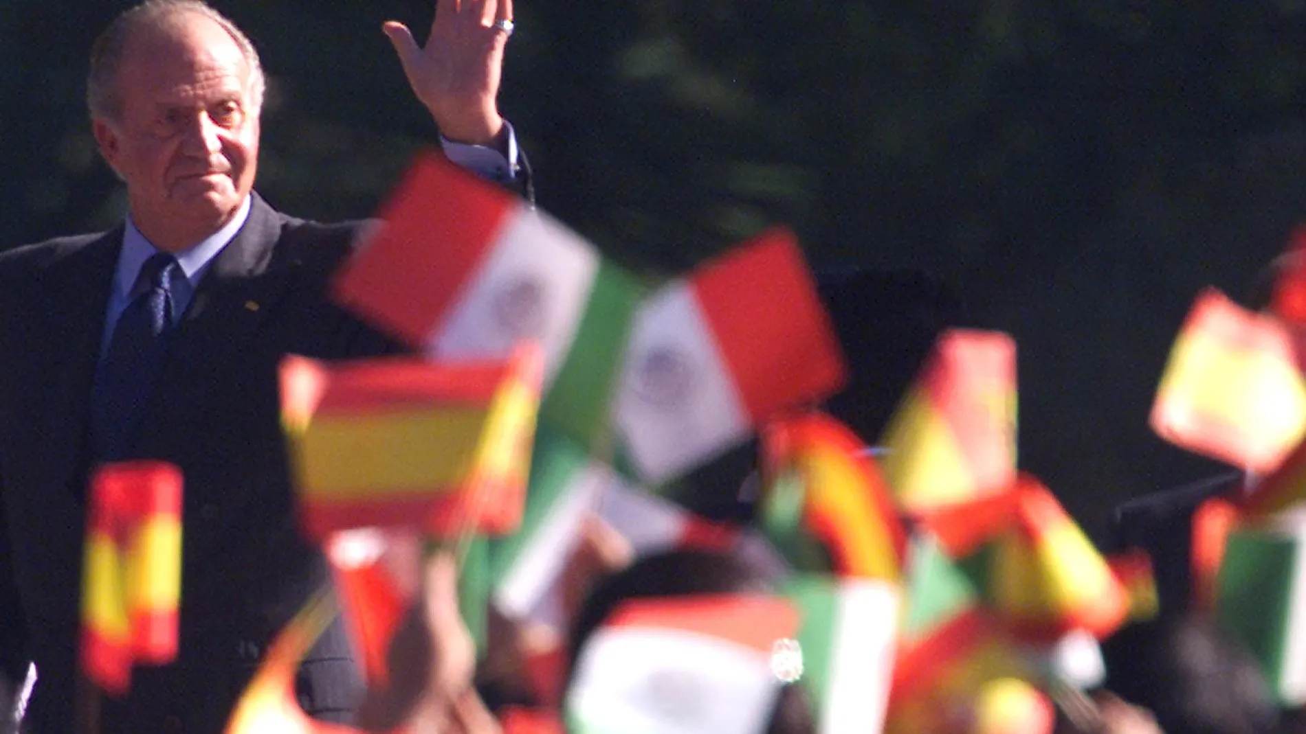 King Juan Carlos of Spain looks at children waving Mexican and Spanish flags during an official reception at the Campo Marte in Mexico City, Monday, Nov. 18, 2002.