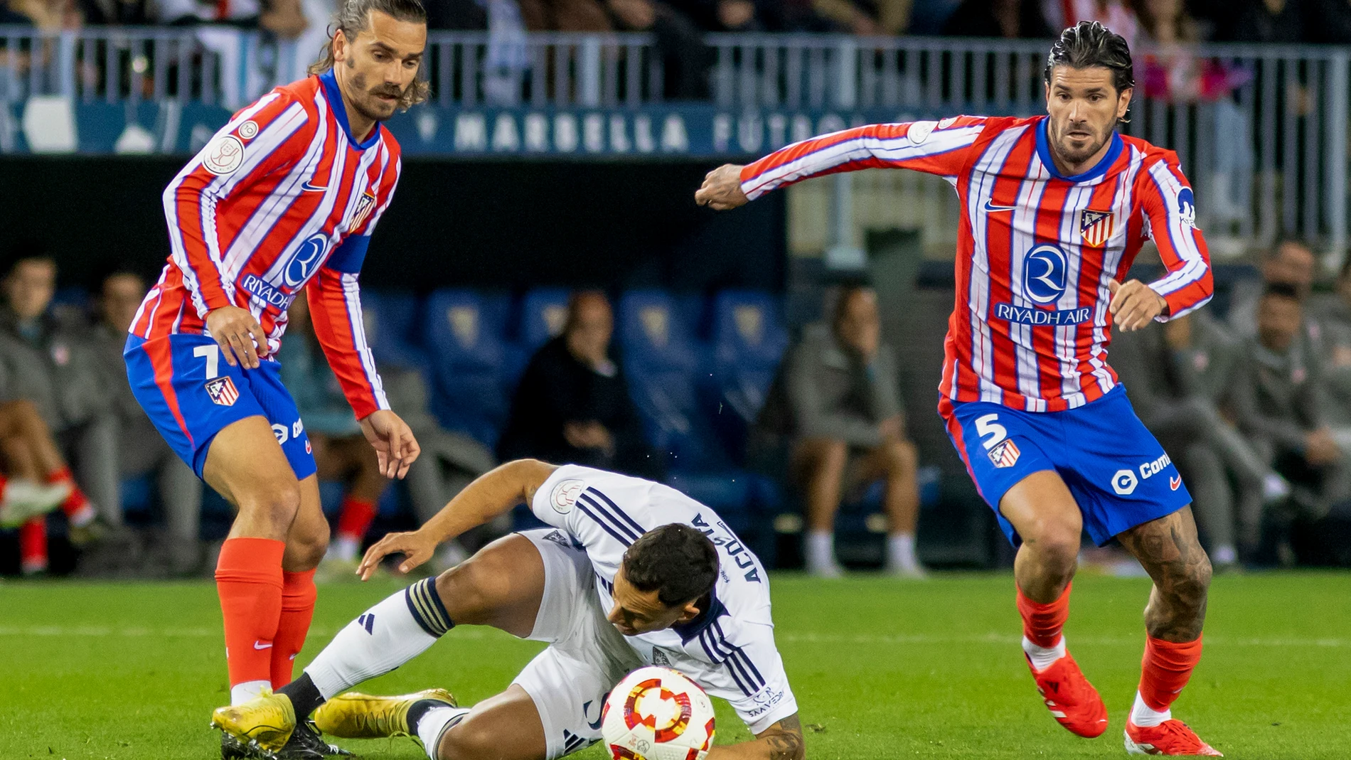 Málaga. 04/01/2025. El delantero francés del Atlético de Madrid, Antoine Griezmann (i), disputa el balón ante el centrocampista del Marbella, Luis Acosta, durante el encuentro correspondiente a los dieciseisavos de final de la Copa del Rey disputado hoy sábado en el estadio de la Rosaleda de Málaga. EFE/Álvaro Cabrera