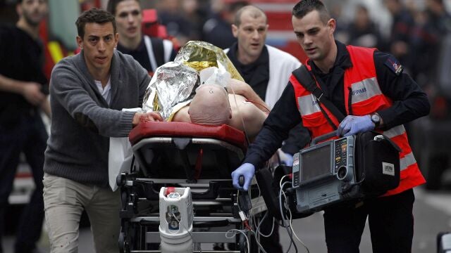 An injured person is evacuated outside the French satirical newspaper Charlie Hebdo's office, in Paris, Wednesday, Jan. 7, 2015. Police official says 11 dead in shooting at the French satirical newspaper. 