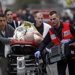 An injured person is evacuated outside the French satirical newspaper Charlie Hebdo's office, in Paris, Wednesday, Jan. 7, 2015. Police official says 11 dead in shooting at the French satirical newspaper. 