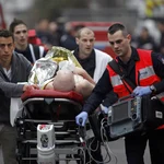 An injured person is evacuated outside the French satirical newspaper Charlie Hebdo's office, in Paris, Wednesday, Jan. 7, 2015. Police official says 11 dead in shooting at the French satirical newspaper.