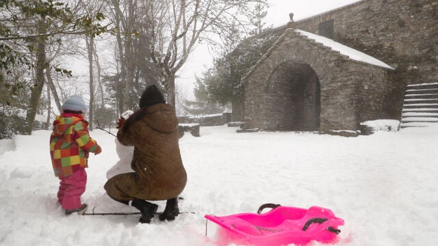 Varias personas realizan un muñeco de nieve en la localidad lucense de O Cebreiro