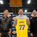 Luka Doncic posa con la camiseta de Los Angeles Lakers junto a Rob Pelinka y JJ Redick, su nuevo entrenador