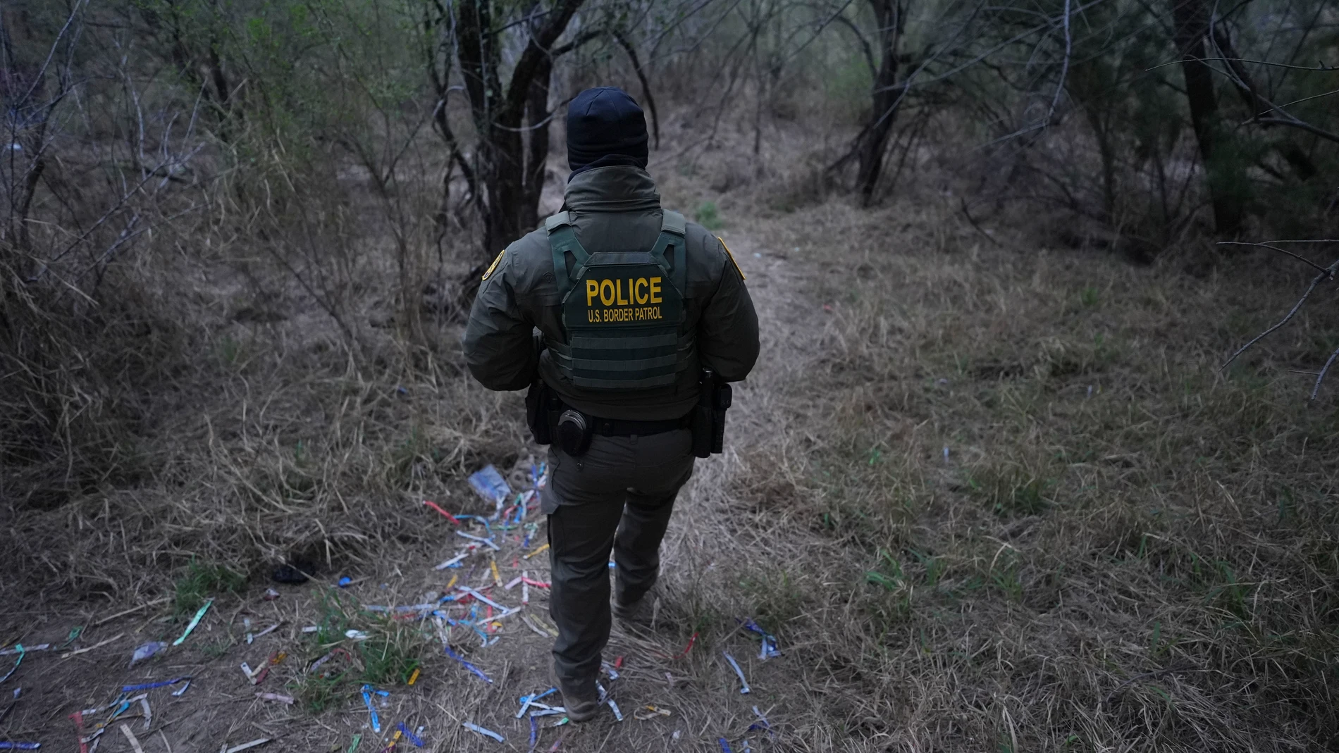 A border patrol agent walks along a trail littered with bracelets used by human smuggling groups near the Rio Grande at the U.S.-Mexico border, Thursday, Feb. 13, 2025, in McAllen, Texas. (AP Photo/Eric Gay)
